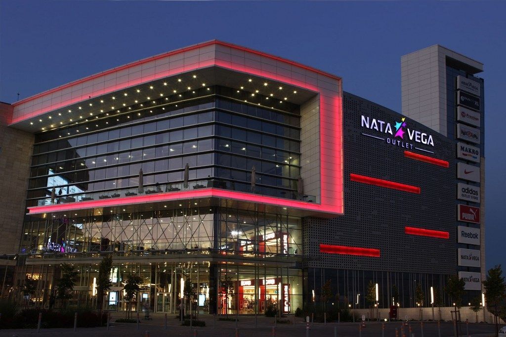 Evening-lit glass facade of Nata Vega Outlet Mall